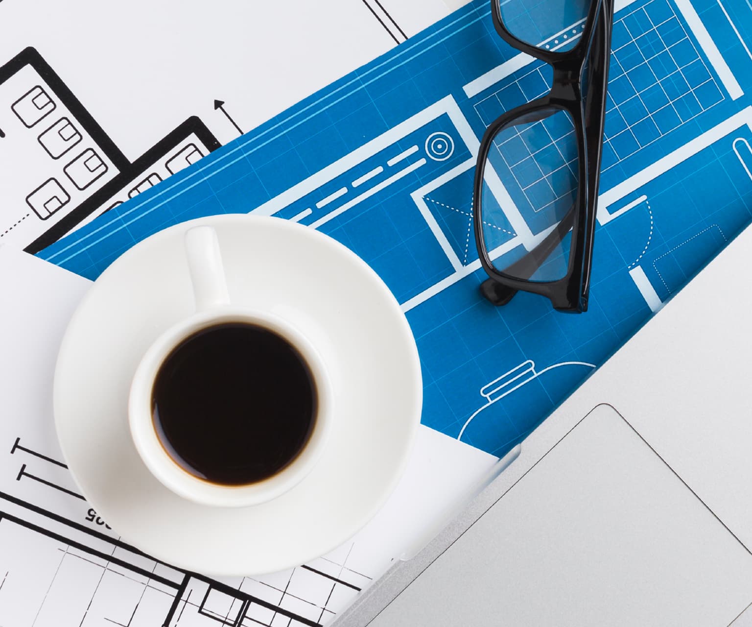 Planos de arquitectura con café y herramientas de trabajo