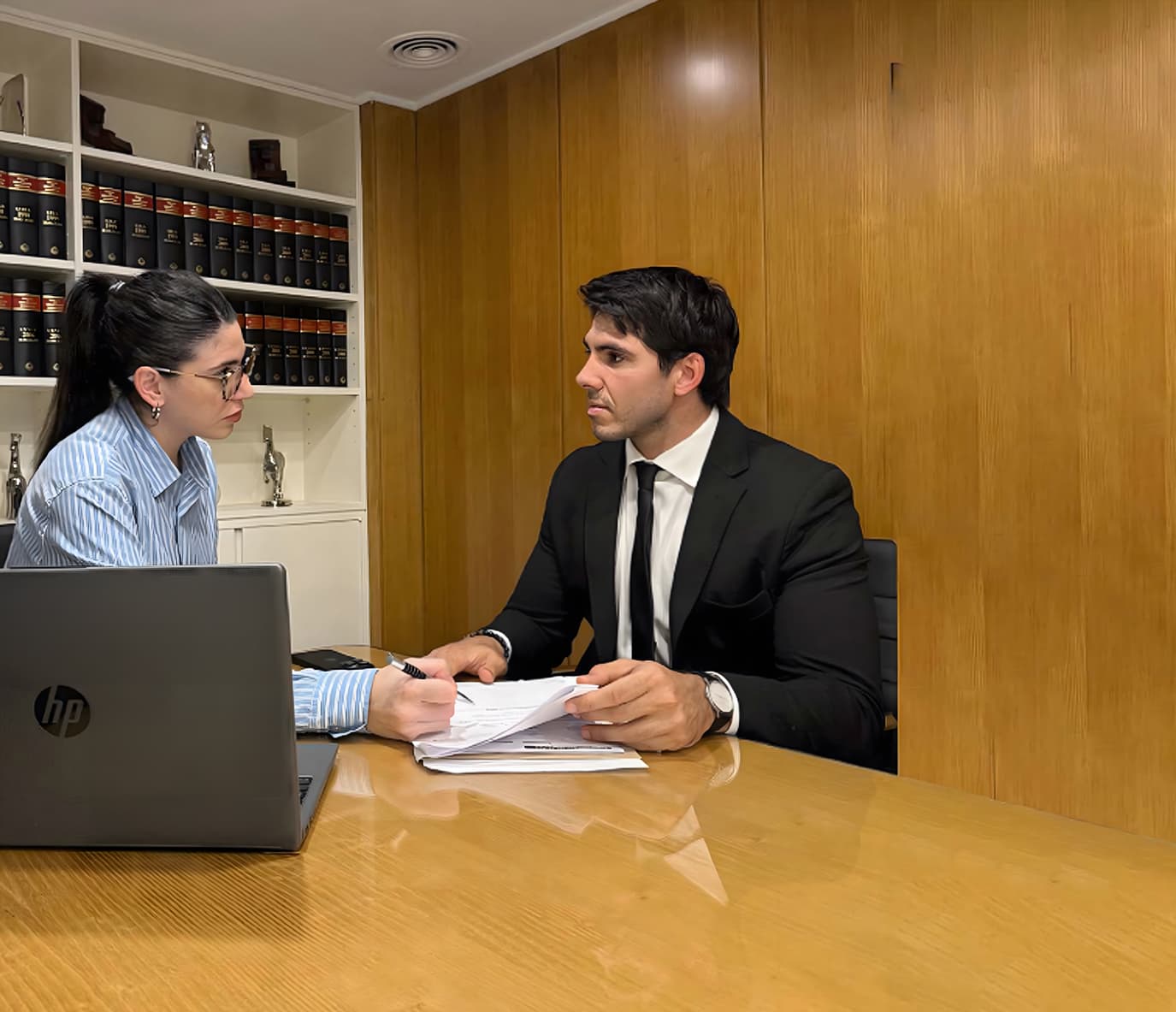 Reunión profesional entre abogada y cliente revisando documentos en una oficina jurídica.